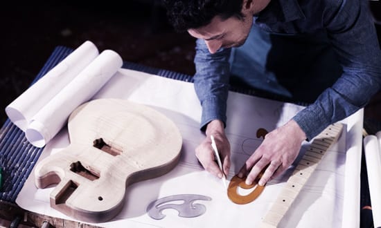 Man making a custom guitar at a content education workshop.
