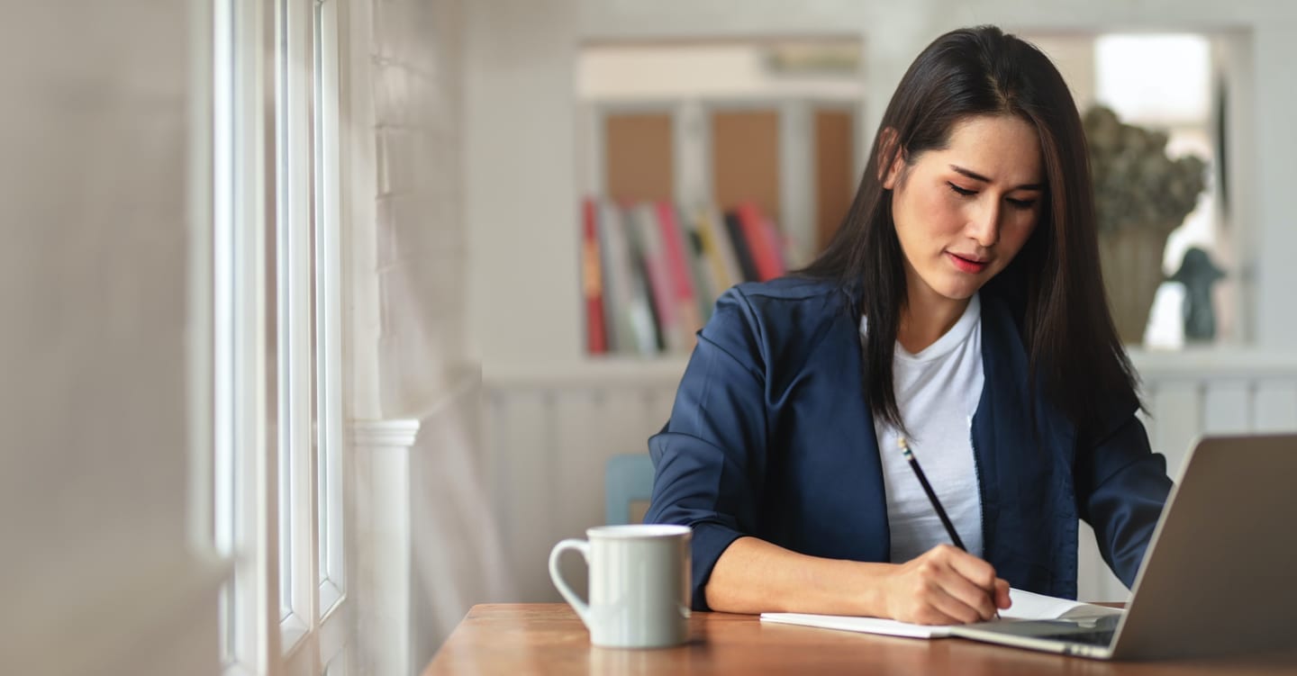 Woman sitting at her desk at home and attending a copywriting course in Singapore online.