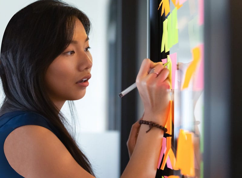 A young Singaporean woman writing on post-it notes at a branded and corporate storytelling course in Singapore.