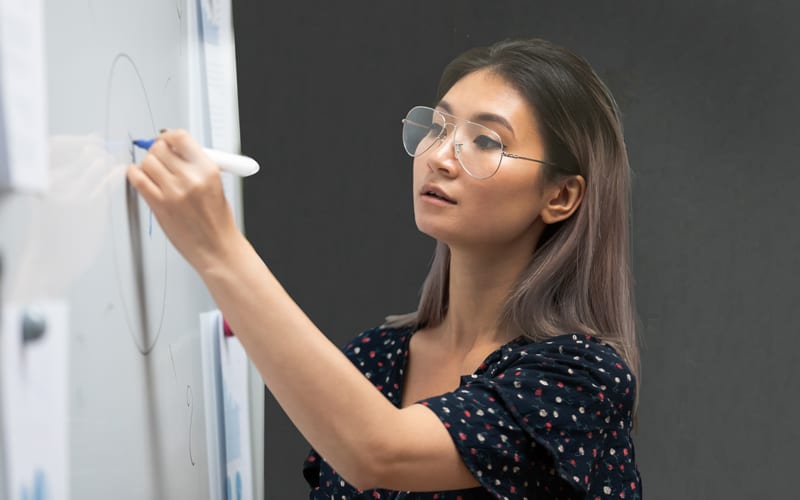 A young Singaporean woman writing on a whiteboard at an information design course in Singapore.