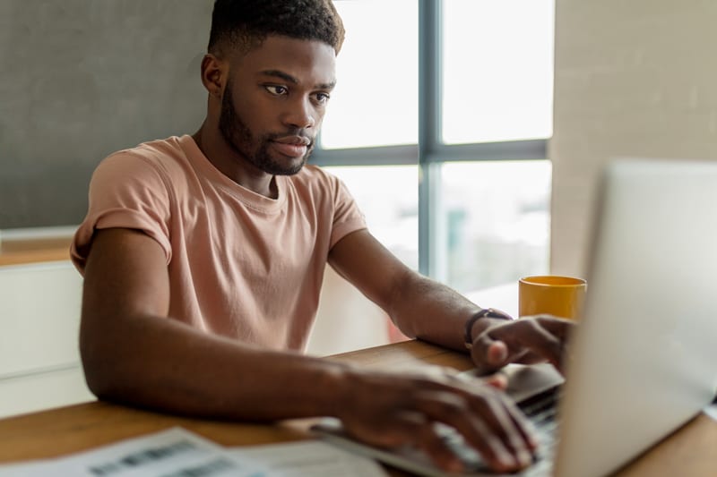 A young African man typing on a laptop at a WordPress course in Singapore.