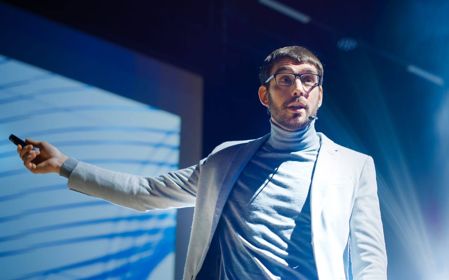 A young man in glasses presenting on a stage at an arts communication course in Singapore.